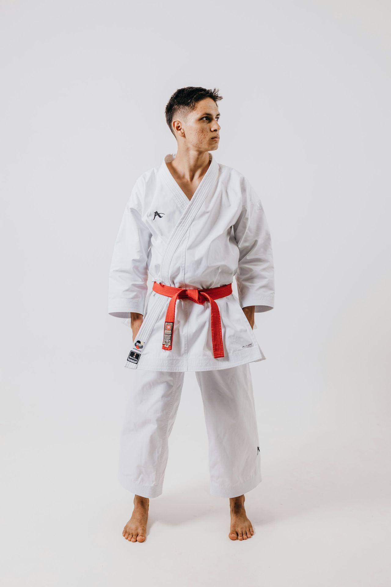 a man wearing a white karate suit and red belt